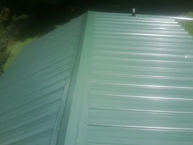 New green metal panels meeting at the ridge of a roof — Flat Roof Repair work by our crew in Apache