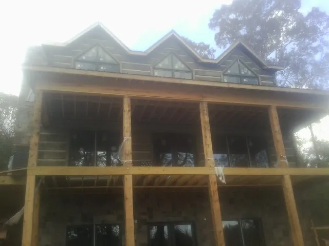 Dormers and porch framing on a large log home under construction — Roof Coating work by our crew in Apache