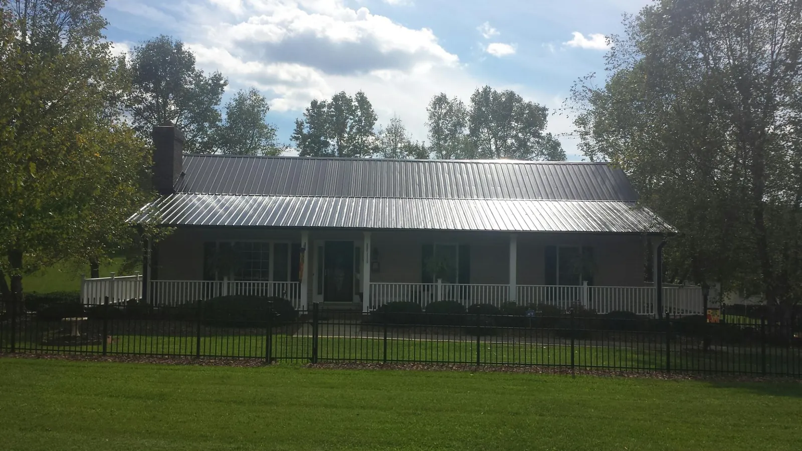 Gray metal roof on a brick ranch with a full width front porch — Gutter Guard Installation work by our crew in Apache