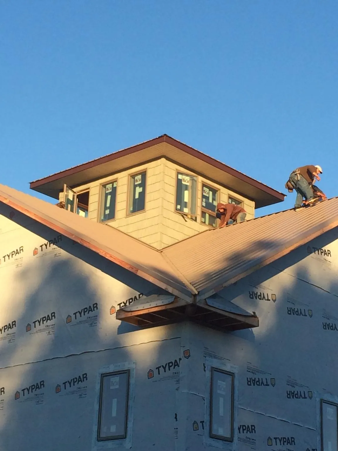 Roofers working around a rooftop cupola on a new metal roof at sunset — Roof Waterproofing in Apache by Roofing Brothers